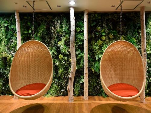 two chairs in front of a green wall with trees at Urabandai Lake Resort Goshiki no Mori in Kitashiobara