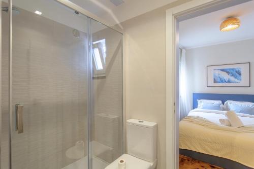 a bathroom with a glass shower and a bed at BeGuest Retiro da Vila - 15min walk from the center - in Abuxarda