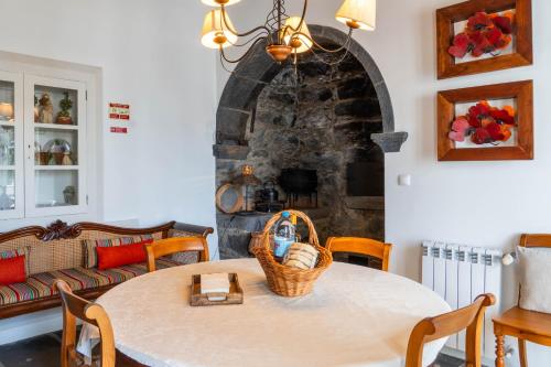 a living room with a table and a stone fireplace at Casa da Árvore in Calhetas