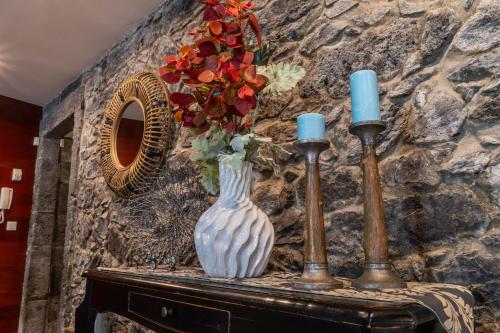 a white vase sitting on a table with two candles at Casa da Árvore in Calhetas