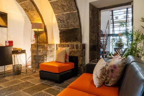 a living room with an orange couch and a chair at Casa da Árvore in Calhetas