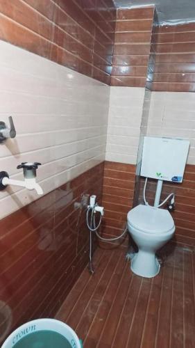 a bathroom with a toilet and a wooden floor at Rajlaxmi Niketan in Ayodhya