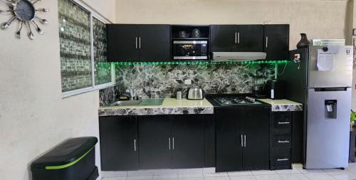eine Küche mit schwarzen Schränken und einem weißen Kühlschrank in der Unterkunft Casa Comfortable and Complete, maximum 8 people in Tierra Colorada