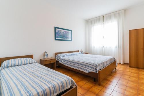 a bedroom with two beds and a window at Residence Acapulco in Porto Santa Margherita di Caorle