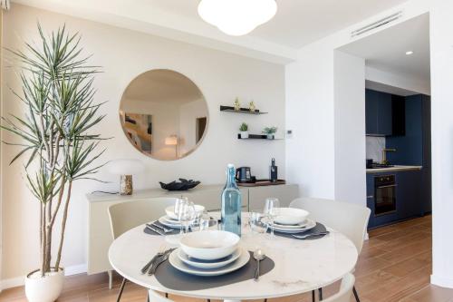 une salle à manger blanche avec une table blanche et un miroir dans l'établissement Juan les pins Suite luxueuse front de mer, à Juan-les-Pins