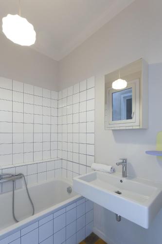 une salle de bain blanche avec un lavabo et une baignoire dans l'établissement Melodie mediterranee - Premiere conciergerie, à Montpellier