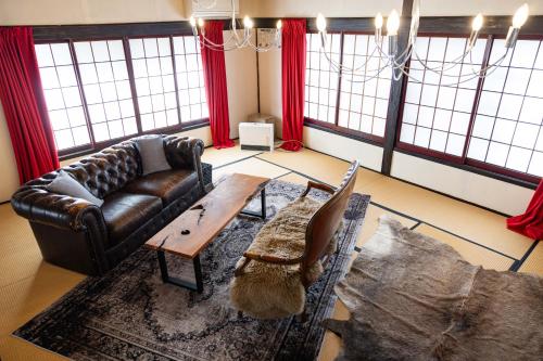 a living room with a leather couch and a table at 小グループ専門貸切一軒家 パーティーOK観光スポット徒歩圏内 小諸駅歩2分揚羽屋 Specializing in small groups, Party OK, Walking to tourist spots, Vacation Rental House 2 min from Komoro sta in Komoro