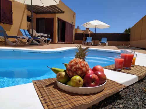 a bowl of fruit on a table next to a pool at Villa Dunas Fuerteventura in Lajares