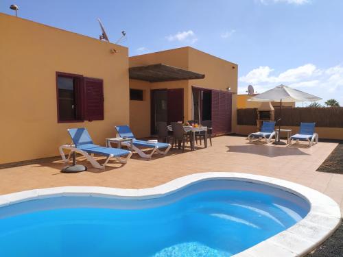 a villa with a swimming pool and a patio at Villa Dunas Fuerteventura in Lajares