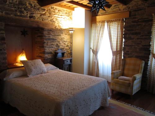 a bedroom with a bed and a chair at A Lareira in Chan de Vilar
