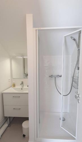 une salle de bain blanche avec une douche et un lavabo dans l'établissement Appartement Ty Cosy, à Quiberon