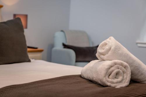a white towel sitting on the edge of a bed at Little Haven - St Andrews Town Centre in St. Andrews