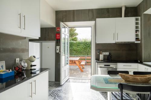 a kitchen with white cabinets and a table at Quinta São José da Relva in Ponta Delgada