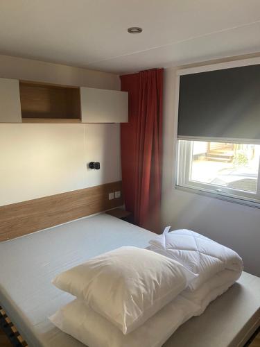 une chambre avec un lit blanc avec une fenêtre dans l'établissement Mobil home vias La Carabasse, à Vias