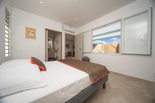 a white bedroom with a bed and a window at 2 Villas avec 2 Piscines in Sainte-Luce