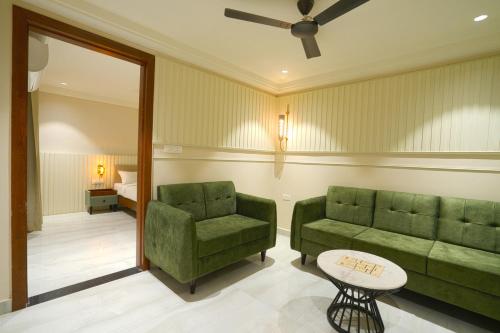 a living room with two green chairs and a table at Hotel Square 36 in Kota