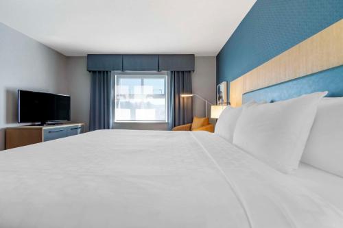 a bedroom with a large white bed and a television at Clarion Hotel & Conference Centre in Abbotsford