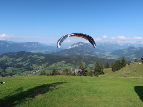 a person flying a parachute on a grassy hill at Schoners Einfanghof by FeWo-PlanWILD005 in Niederau