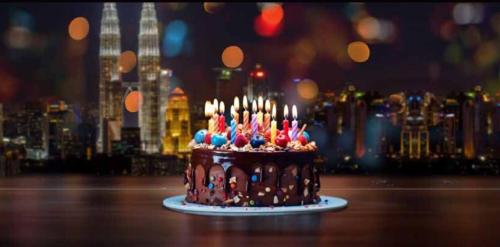 a chocolate cake with lit candles on a table at Hilton Garden Inn Kuala Lumpur - North in Kuala Lumpur