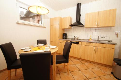 eine Küche mit einem Holztisch mit Stühlen und einem Waschbecken in der Unterkunft "Haus Stefanie" Bungalow -1- in Dahme
