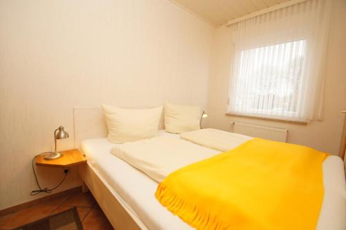 ein Schlafzimmer mit einem Bett mit einer gelben Decke darauf in der Unterkunft "Haus Stefanie" Bungalow -1- in Dahme