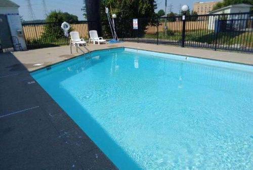 a large blue swimming pool with two white chairs at Howard Johnson by Wyndham Clarksville Tennessee in Clarksville
