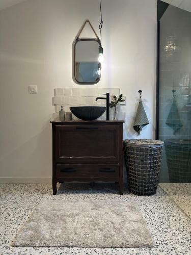La salle de bains est pourvue d'un lavabo et d'un miroir sur une commode. dans l'établissement La Cabane du Mascaret, à Vayres