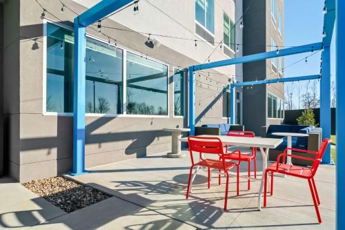 a patio with red chairs and a table in front of a building at Tru By Hilton Rogers Bentonville in Rogers