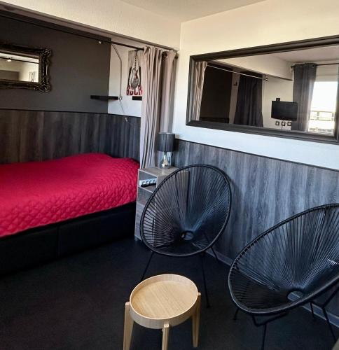 - une chambre avec deux chaises et un lit rouge dans l'établissement LE PETIT LIBERT 1 - Votre studio à Port Soleil au Village Naturiste, au Cap d'Agde