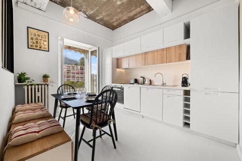 une cuisine avec des armoires blanches et une table et des chaises dans l'établissement L Écrin du Palace, cosy 2 pièces, à Menton