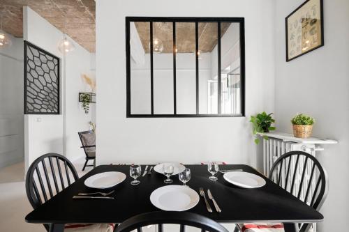 une salle à manger avec une table et des chaises noires dans l'établissement L Écrin du Palace, cosy 2 pièces, à Menton