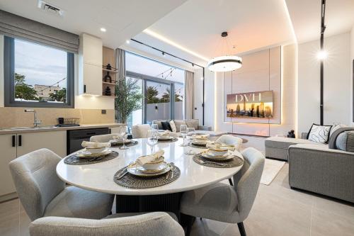 a dining room and living room with a table and chairs at Luxury 4BR Villa, Bali Pool Retreat, Ruba A Ranches 3 in Dubai