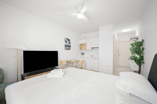 - une chambre blanche avec un grand lit et une cuisine dans l'établissement Studio pour deux très jolie au centre ville, à Menton