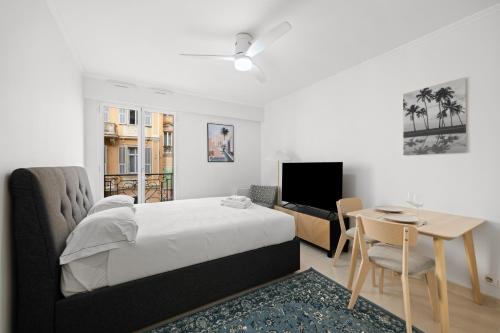 une chambre avec un lit, une table et une télévision dans l'établissement Studio pour deux très jolie au centre ville, à Menton