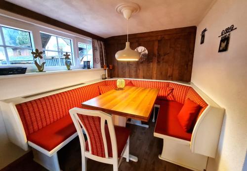 a dining area with a wooden table and red chairs at Gurkhof Ferienwohnungen in Gnesau