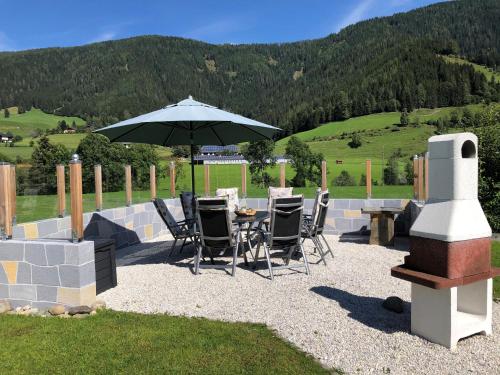 a patio with a table and chairs and an umbrella at Gurkhof Ferienwohnungen in Gnesau