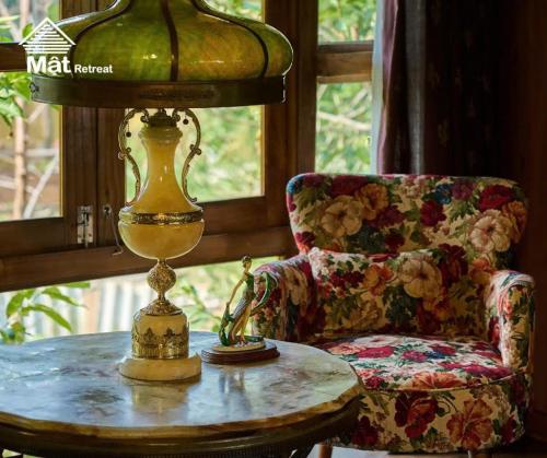 a lamp sitting on a table next to a chair at Mật Retreat in Ba Vì