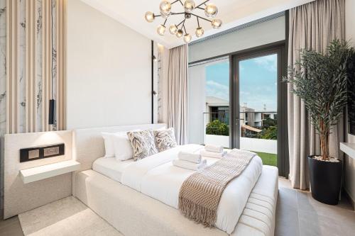 a white bedroom with a white couch and a large window at Luxury 4BR Villa, Bali Pool Retreat, Ruba A Ranches 3 in Dubai