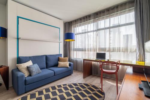 a living room with a blue couch and a desk at Naitly Barcelona Poblenou in Barcelona