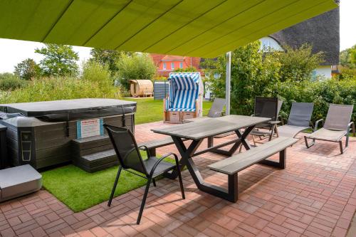 a patio with a grill and a picnic table and chairs at C 6 Reethaus Strandkorb mit Außenwhirlpool und Sauna in Gramkow