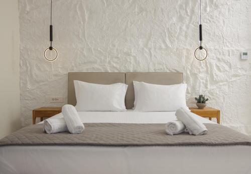 a bed with white pillows and two towels at Pnoe Villas Syros in Megas Yialos-Nites
