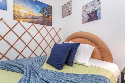 a bed with two blue pillows on top of it at BeGuest Caparica Cozy Apartment in Costa da Caparica