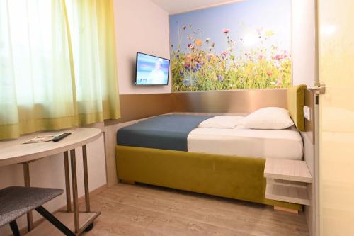 a bedroom with a bed and a desk and a painting at HOTEL Am Spichernplatz in Düsseldorf