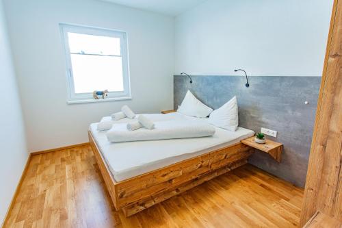 ein Schlafzimmer mit einem Bett mit weißen Laken und einem Fenster in der Unterkunft Happy Aich 2 by Alpenidyll Apartments in Aich