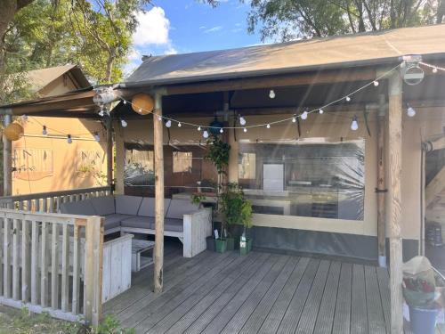 a pergola with a bench and a table on a deck at Glampingtent de Saskerlei, de Woudhaven in De Woude