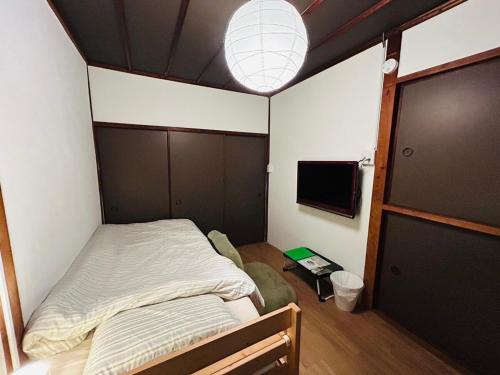 a small bedroom with a bed and a flat screen tv at TSUBAME 103 staying private home in Osaka
