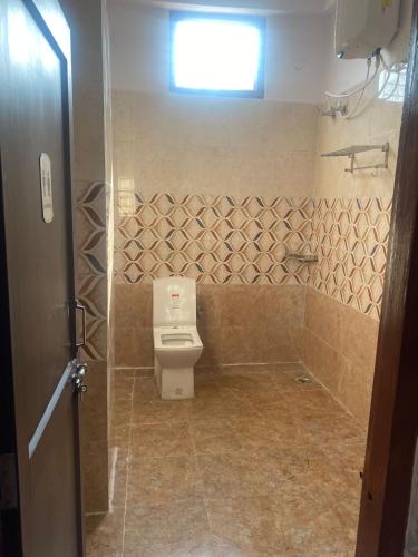 a bathroom with a toilet and a window at HappyInn in Ayodhya