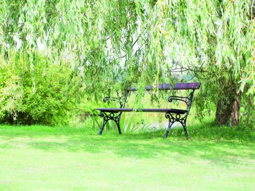 a park bench sitting in the grass under a tree at Fewo 2 "Landhaus am Grashof" in Offenbüttel