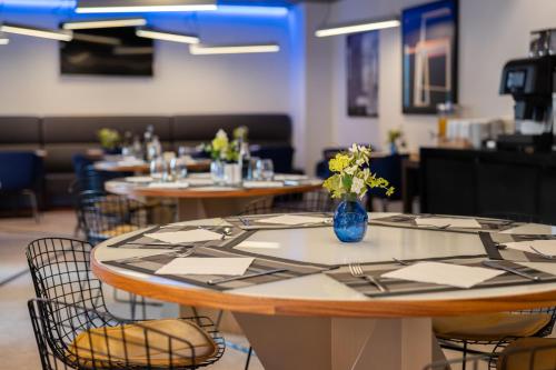 a room with tables and chairs with a vase of flowers at Naitly Barcelona Poblenou in Barcelona