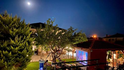 Una casa con un árbol en un patio por la noche en Marilia & Myronas Lemnos Apartments, en Mirina